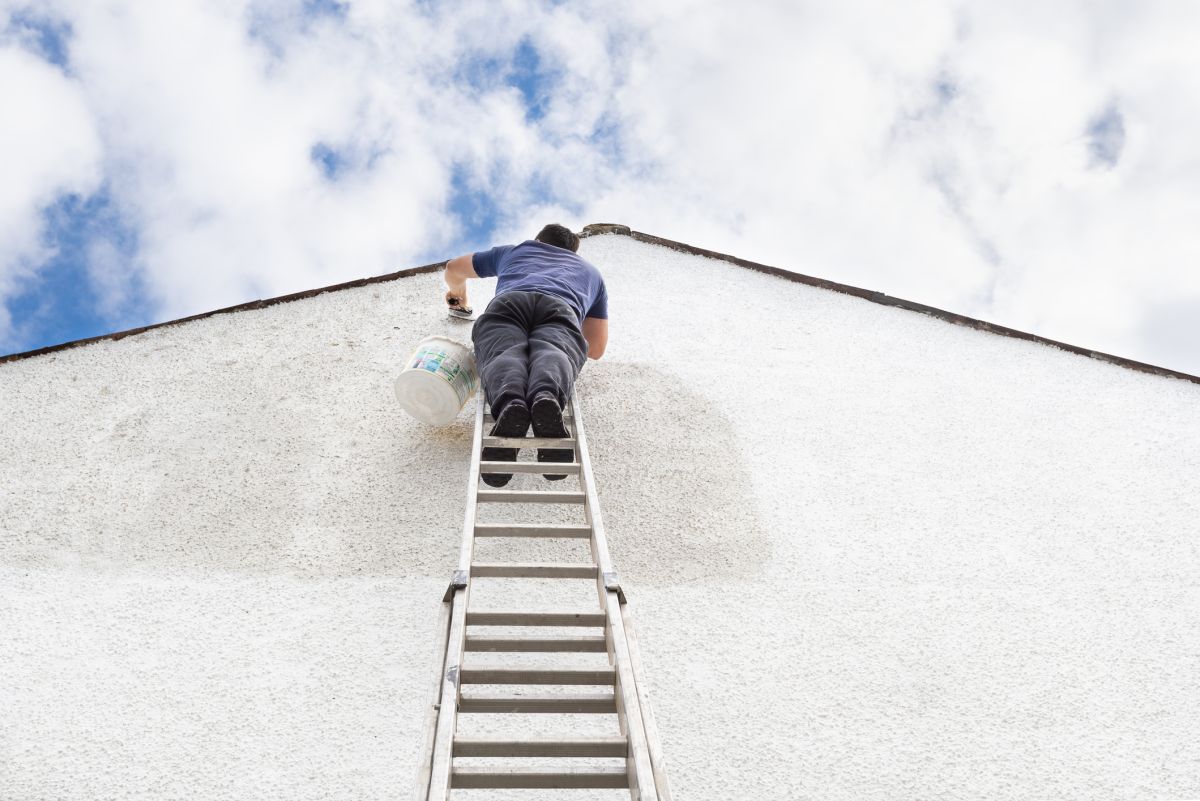 painting gable end of house with ladder