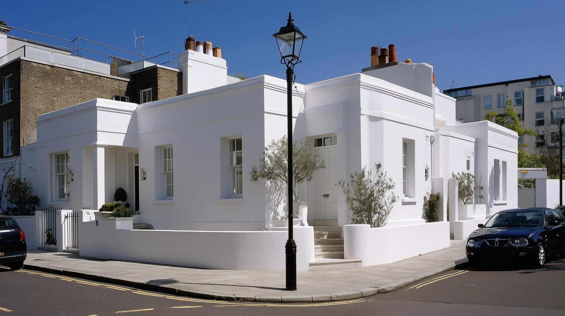 Beautifully rendered white corner house with smooth exterior wall finish under clear blue sky.