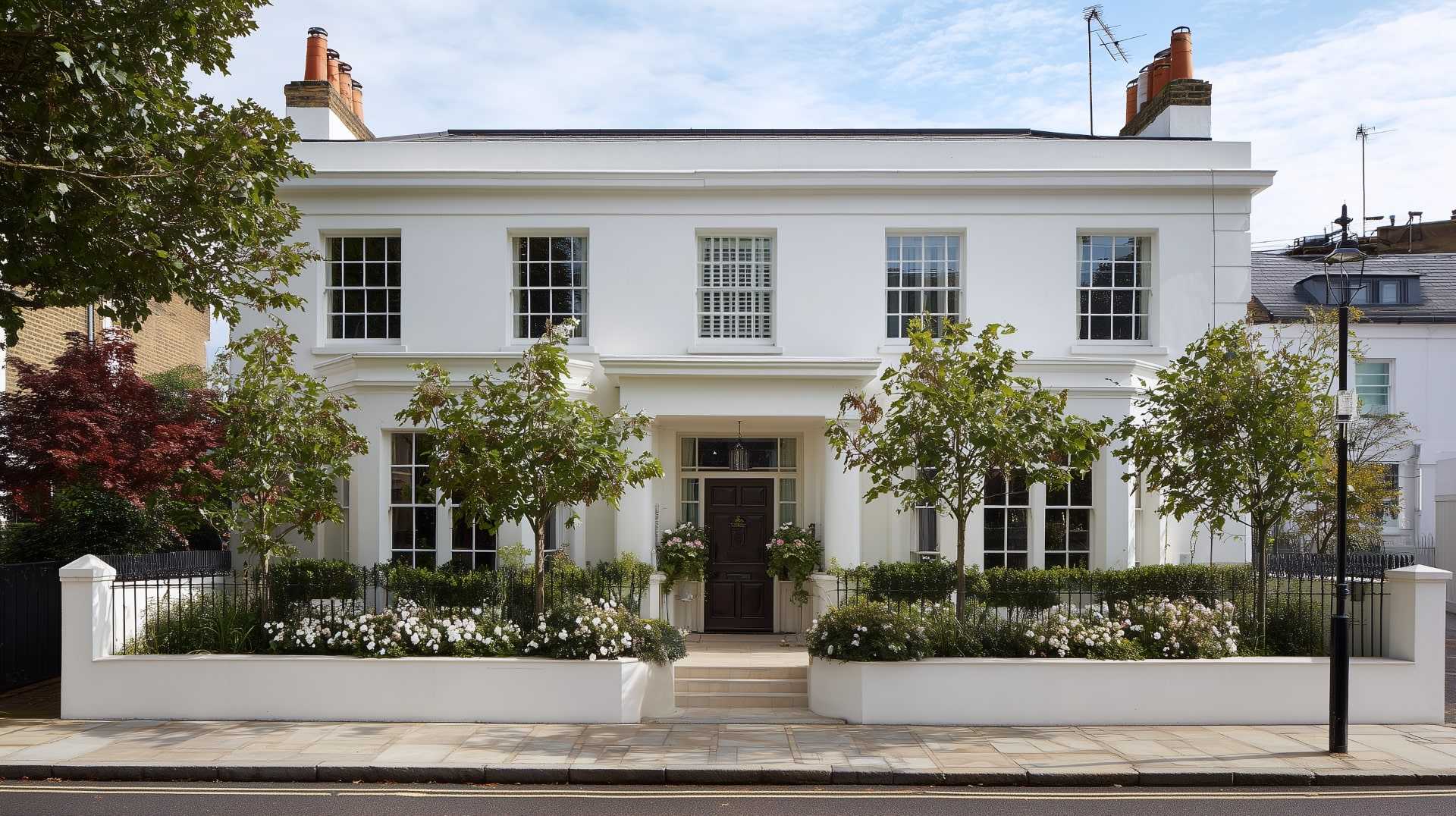 Elegant white house paint exterior on a corner lot, featuring a black front door and classic sash windows.